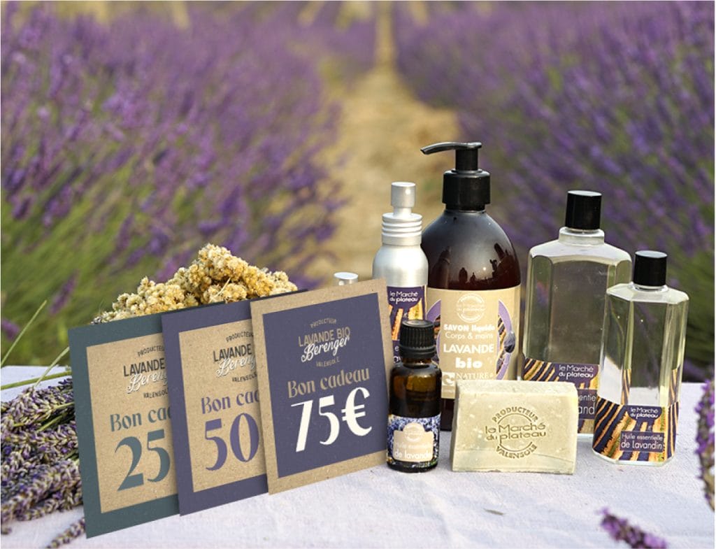 Une sélection de produits de beauté et de cartes-cadeaux sur le thème de la lavande, présentés sur un tissu blanc avec un champ de lavande en arrière-plan. Les cartes-cadeaux ont une valeur de 25 €, 50 € et 75 €.
