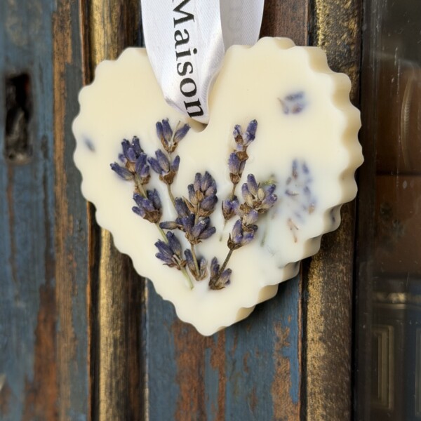 Lavendeltee: das Rezept, die richtige Dosierung und unsere Tipps 9 Le Galet Cœur Lavande | Édition Artisanale est un ornement de cire en forme de cœur, fabriqué à la main avec des fleurs de lavande séchées et une touche de macérat, suspendu par un ruban blanc sur du bois rustique.